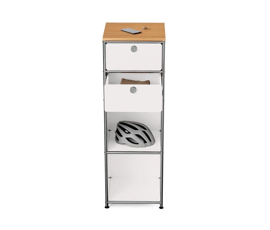 Schmale, weiße Metallkommode »CN3« mit Holzplatte und zwei Schubladen; ein Fahrradhelm liegt im Regal.