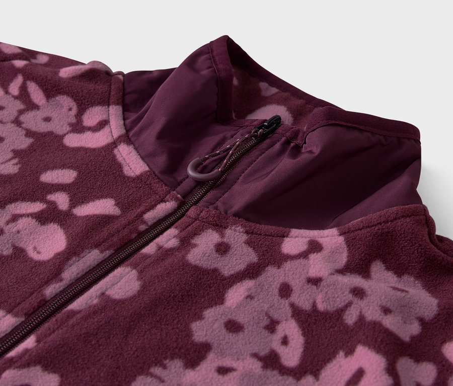 Detailaufnahme einer lilafarbenen Fleecejacke mit Blumenmuster und Reißverschluss.