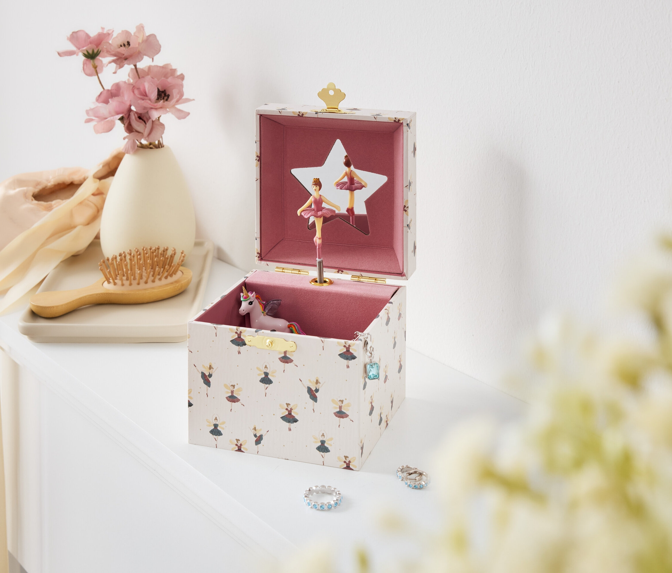 Offene Spieluhr mit Ballerinen und Einhorn auf einem weißen Tisch.