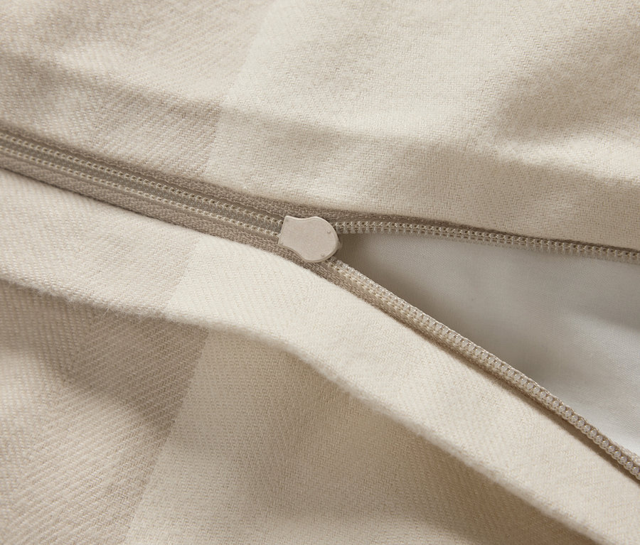 Detailaufnahme eines beigen Bettbezugs mit Reißverschluss.