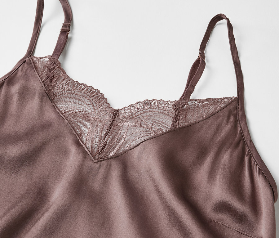 Detailansicht eines violetten Satintops mit Spitze am Ausschnitt.