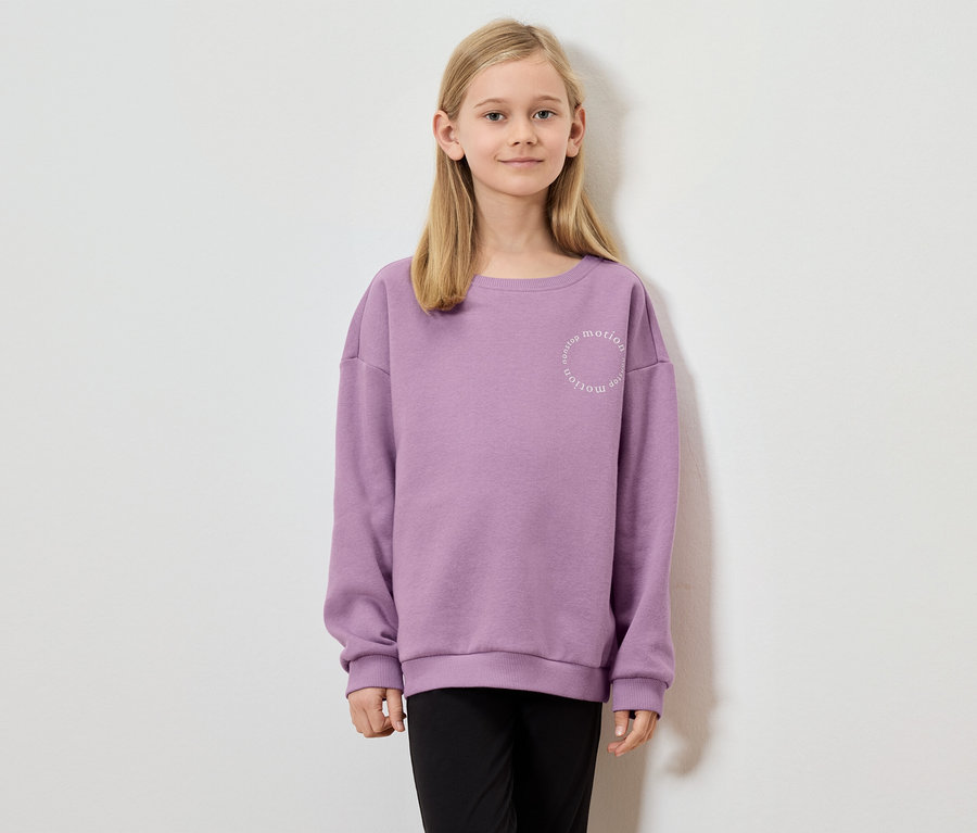 Mädchen mit blonden Haaren trägt ein lila Sweatshirt mit der Aufschrift "nonstop motion".