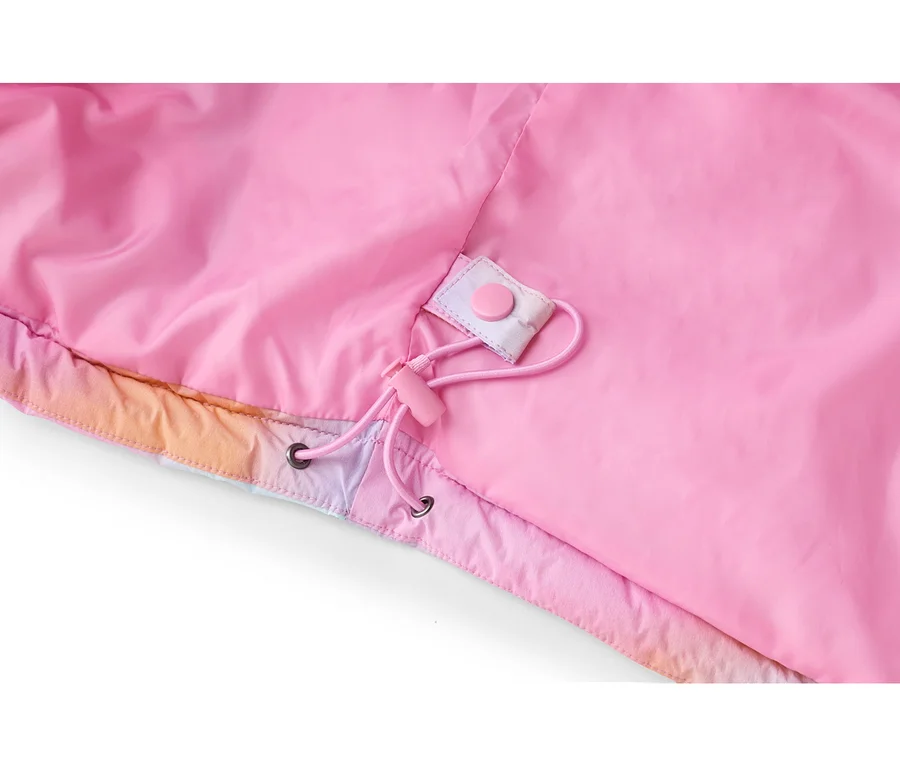 Nahaufnahme einer pinken Jacke mit pinkem Futter und einem Kordelzug mit pinkem Stopper und Ösen. Der untere Rand der Jacke zeigt ein farbenfrohes Farbverlaufsmuster in Pink, Orange und Lila, mit einem pinken Druckknopf an einer Stofflasche.