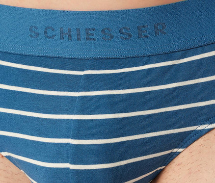 Mann trägt blau-weiß gestreifte SCHIESSER Rio-Slips. Der blaue Bund ist mit dem SCHIESSER-Logo versehen.