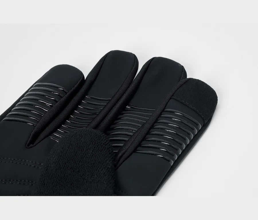 Nahaufnahme eines schwarzen Handschuhs mit griffigen Streifen auf den Fingern und weichem Material am Daumen.