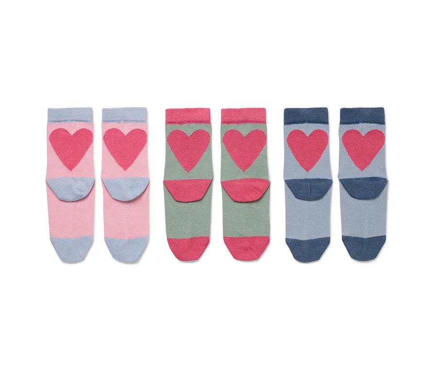 Drei Paare Socken mit rosafarbenen Herzen auf rosa, grün und blau.
