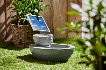 Grauer Solar-Gartenbrunnen mit zwei Schalen auf Gras.