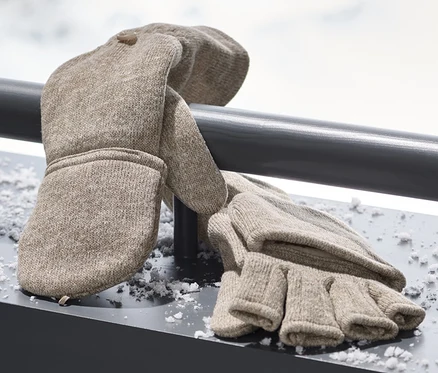 Beige Strickfleece-Klappfäustlinge liegen auf einer verschneiten Oberfläche.