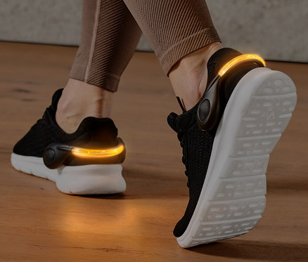 Beine mit 2 LED-Schuhclips an schwarzen Schuhen.