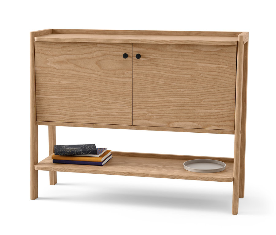 Helle Anrichte aus Holz mit zwei Türen und einem Regal, auf dem Bücher und ein Teller liegen.