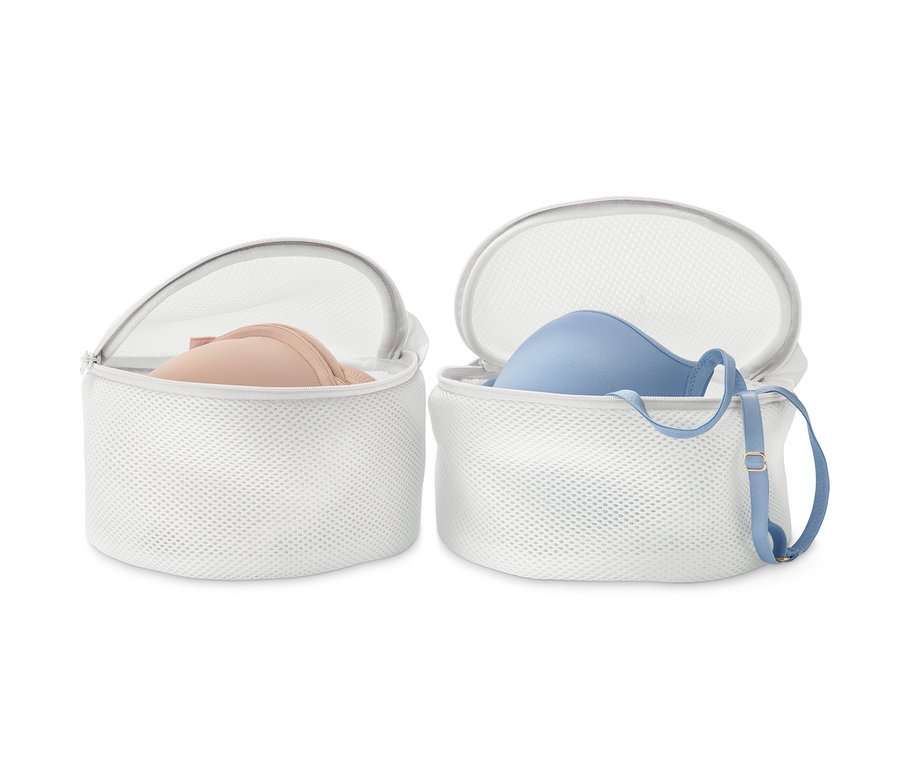 Zwei weiße BH-Wäschenetze, in denen sich jeweils ein BH befindet.