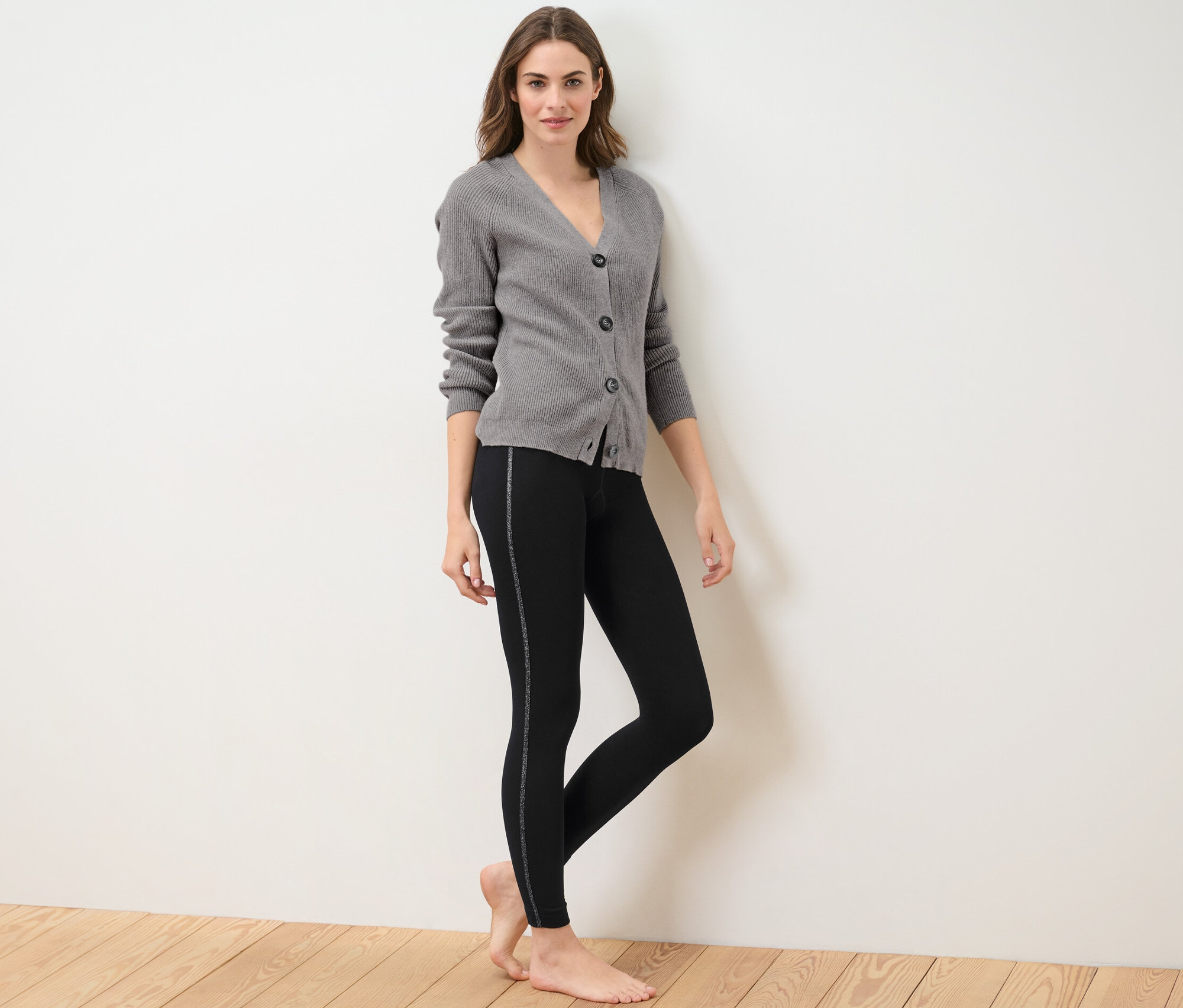 Frau posiert in Thermoleggings mit Glitzertape und grauem Cardigan.