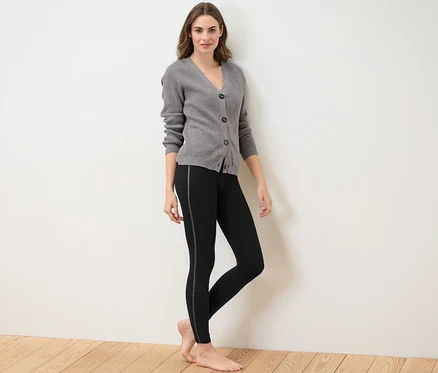 Frau posiert in Thermoleggings mit Glitzertape und grauem Cardigan.