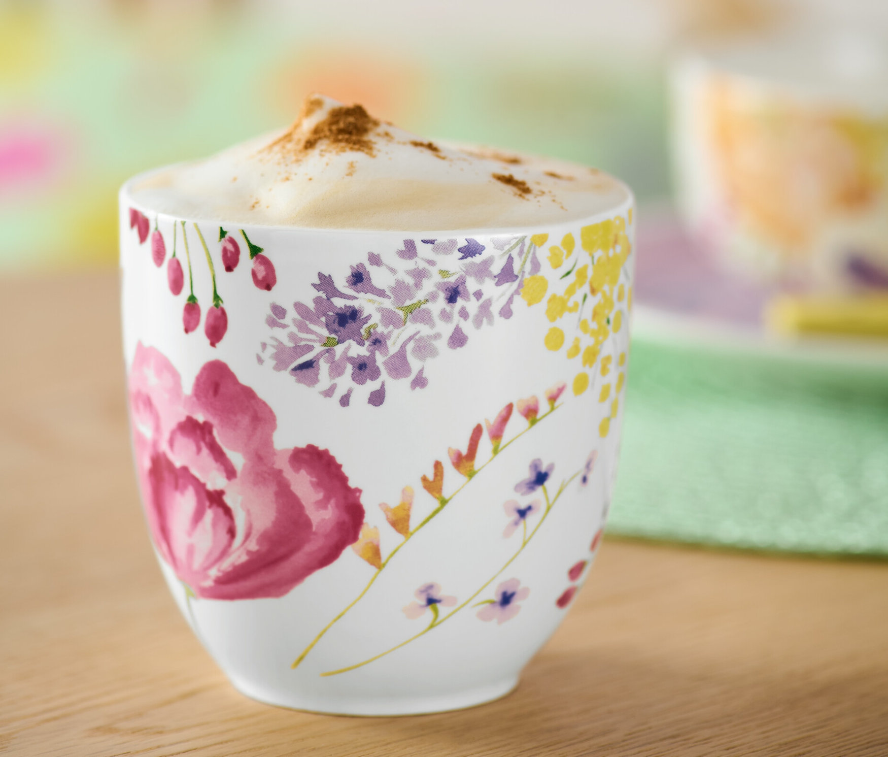 Detailansicht eines Bechers mit Kaffee und Blumenmuster.