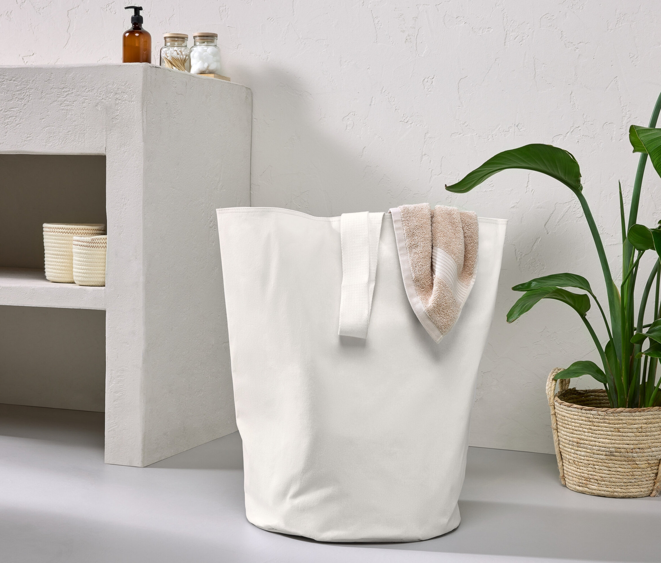 Ein weißer Aufbewahrungskorb mit Trageband und ein gefaltetes Handtuch.