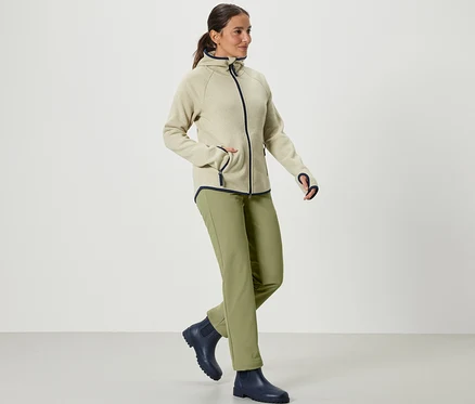 Frau geht und trägt eine Softshellhose in Khaki.