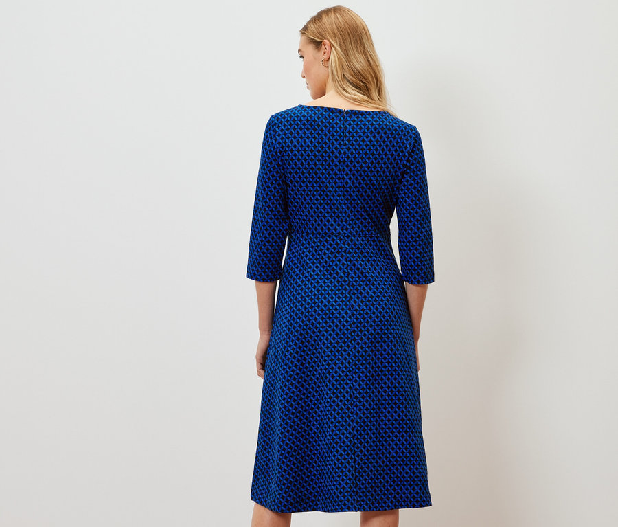 Rückansicht einer Frau in einem bedruckten Jerseykleid.