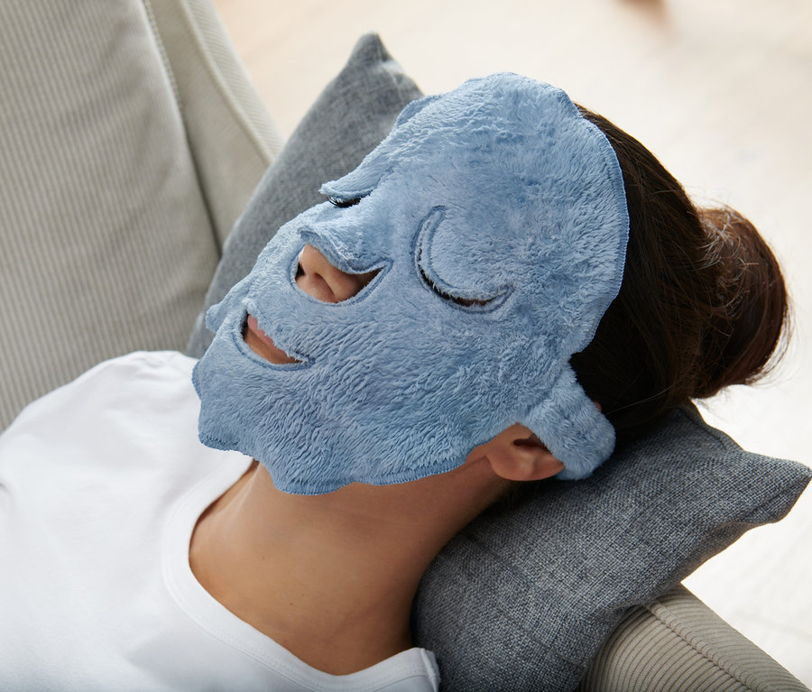 Frau liegt mit blauer 2 Gesichtsmasken auf Kissen.