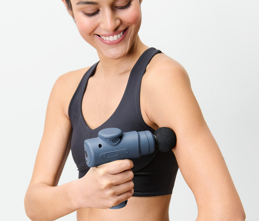 Frau benutzt Mini-Massagepistole am Arm.