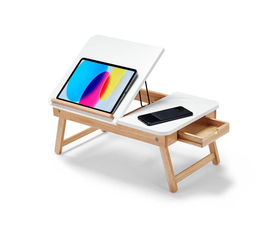 Ein Laptop-Betttisch mit weißer Tischplatte und hellbraunen Holzbeinen. Auf der Tischplatte liegen ein Tablet und ein Handy.