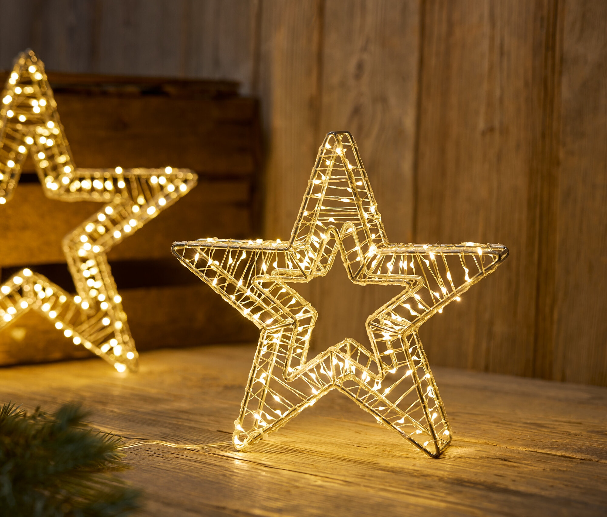 Beleuchtete Drahtsterne auf einer Holzoberfläche.