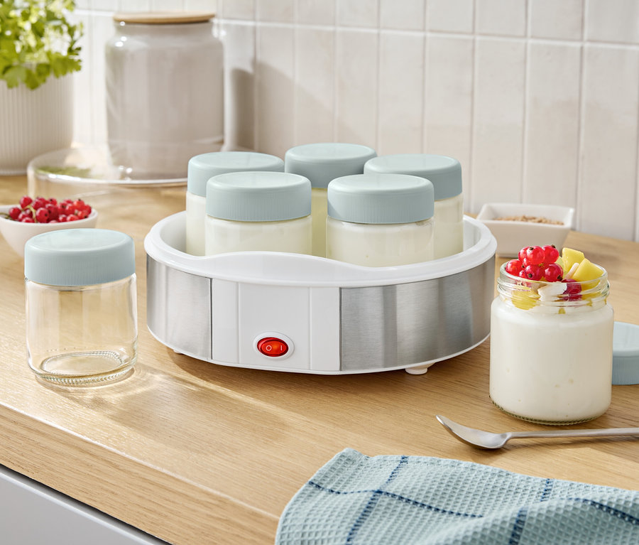 Joghurtbereiter mit sechs Gläsern und einem Glas Joghurt mit Früchten.