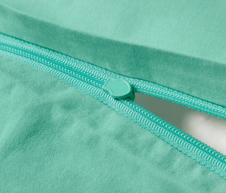 Nahaufnahme von türkisgrüner Renforcé-Bettwäsche mit Reißverschluss.