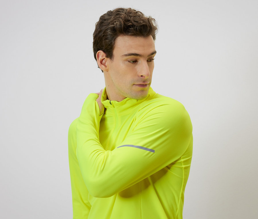 Mann in neon-gelber Jacke massiert seinen Nacken.