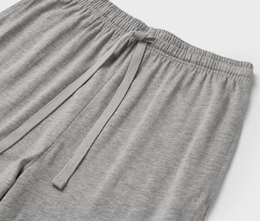 Detailaufnahme einer grauen Jogginghose mit elastischem Bund und Kordelzug.