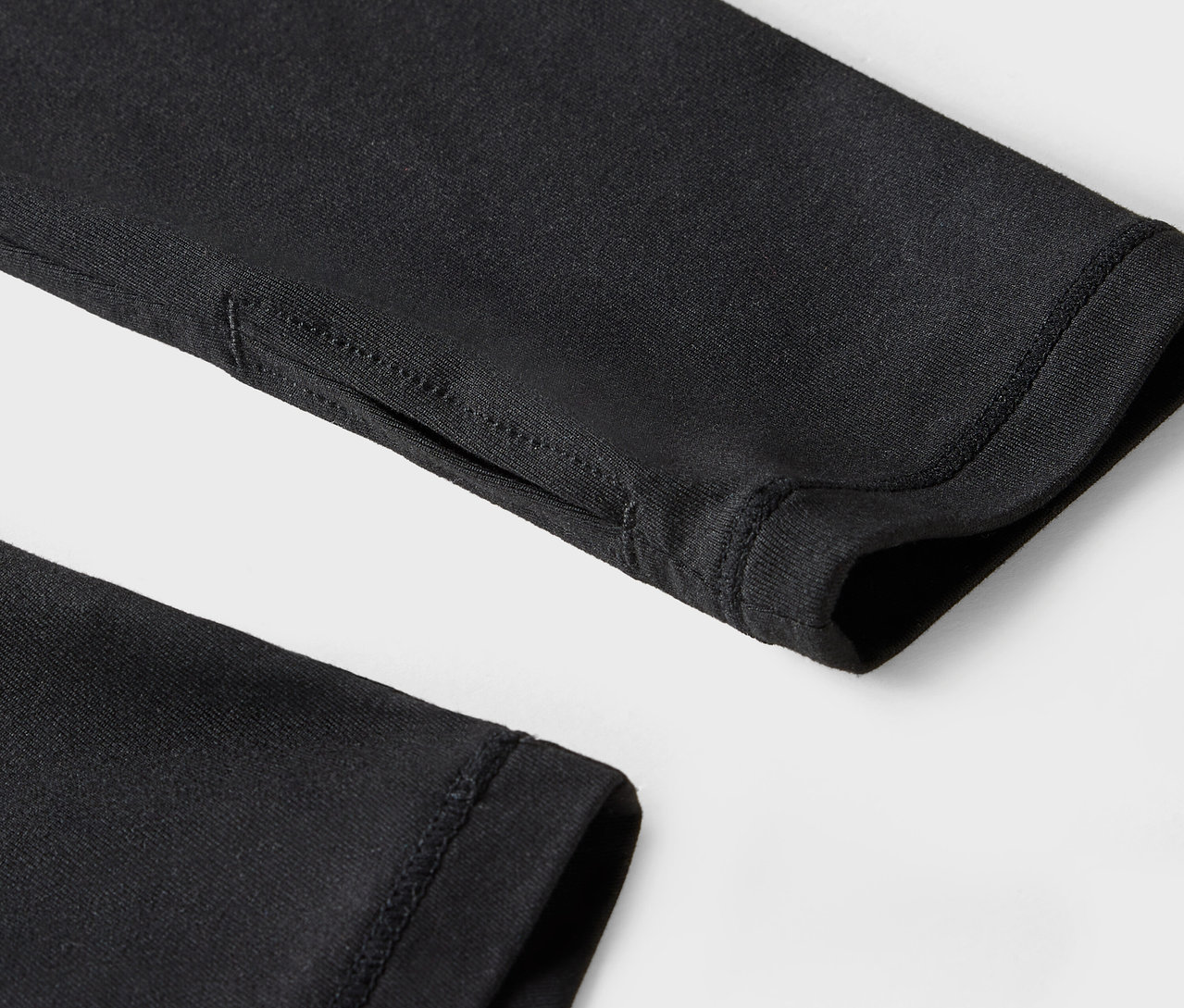 Detailaufnahme eines schwarzen Ärmels mit Daumenloch.