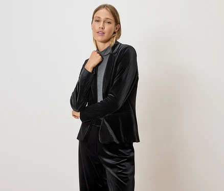 Frau posiert in schwarzem Samt-Blazer und Hose.