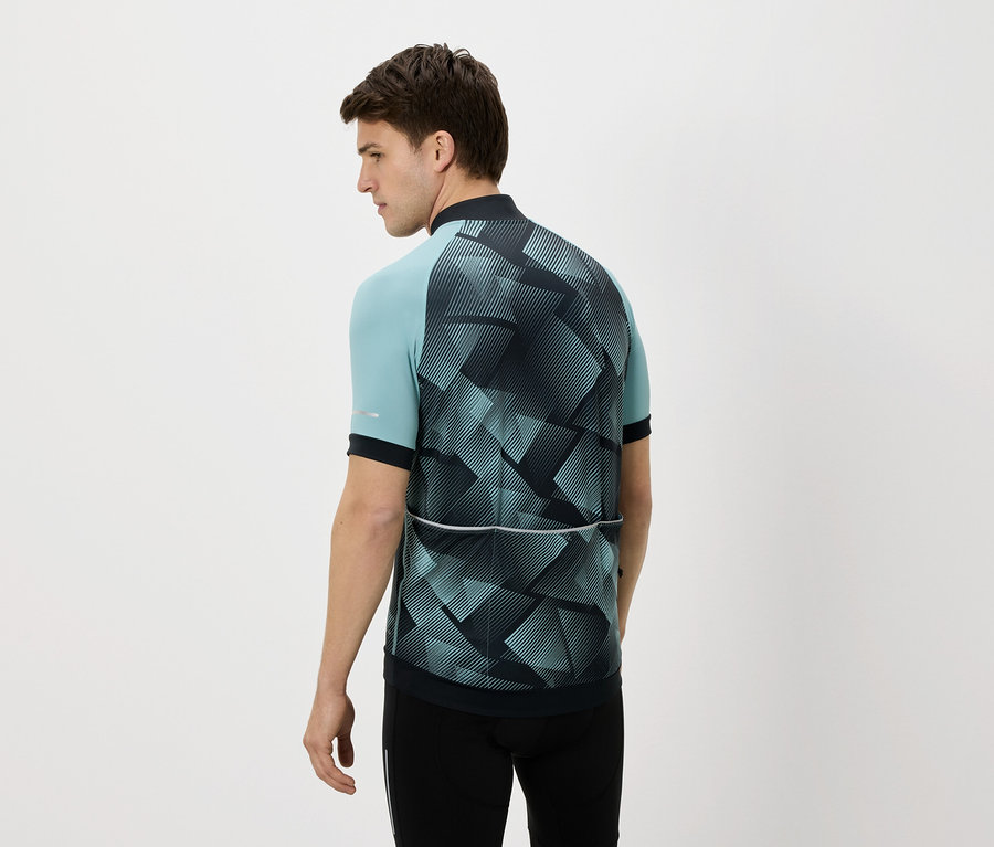 Mann von hinten in einem blau-schwarzen Radtrikot und schwarzen Hosen vor einem weißen Hintergrund.