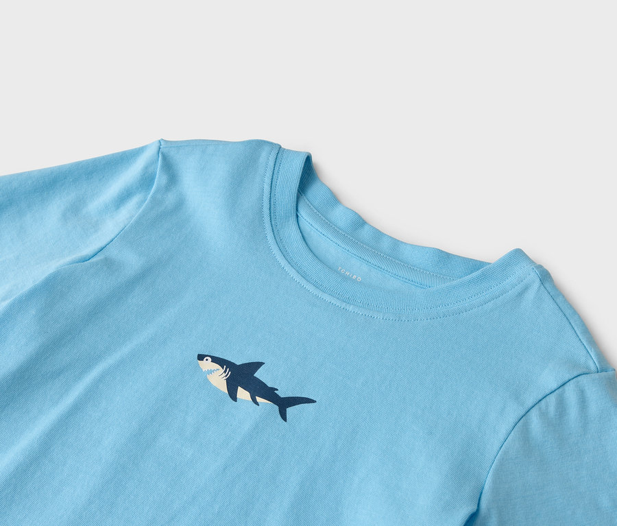 Nahaufnahme eines hellblauen T-Shirts mit einem Hai-Motiv.