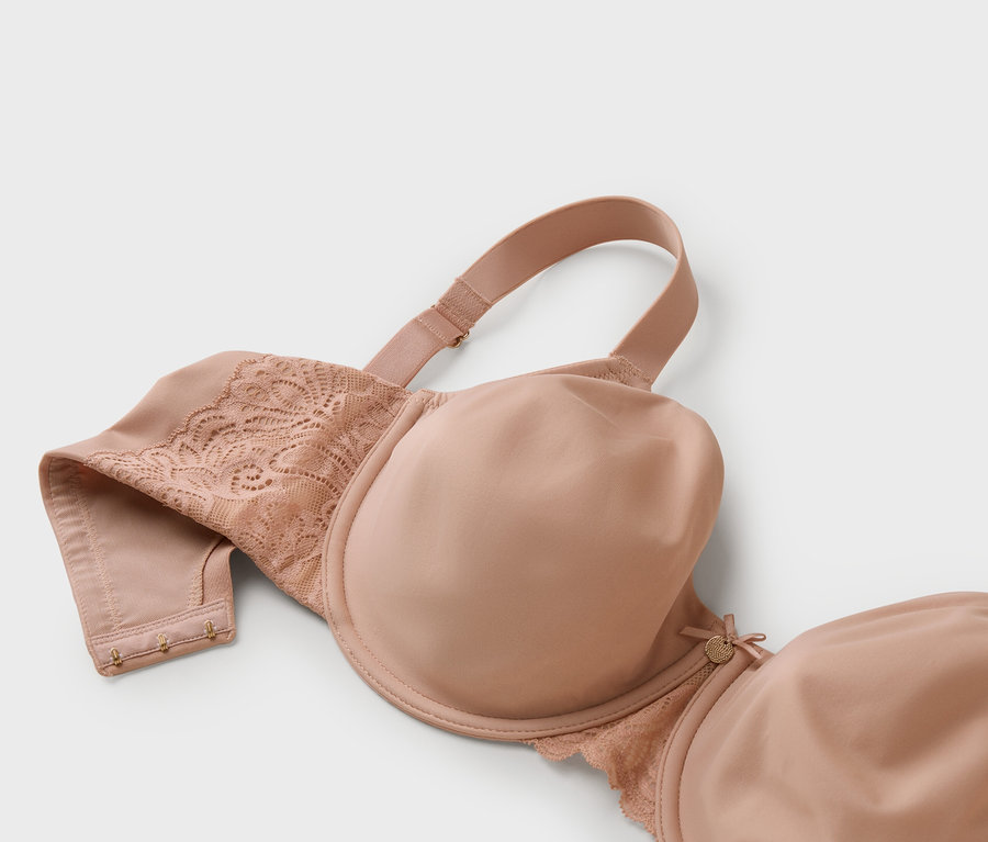 Nahaufnahme eines nudefarbenen BHs mit Spitze auf grauem Hintergrund.
