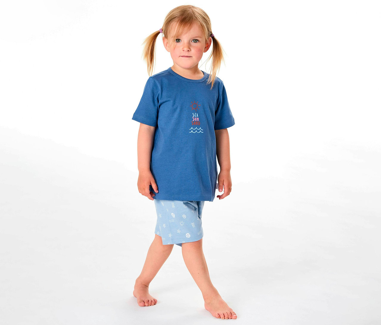 Mädchen trägt einen kurzen Kinder-Pyjama von SCHIESSER mit blauem Oberteil und hellblauer Hose mit Muster.