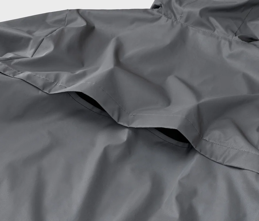 Nahaufnahme einer grauen Regenjacke mit Kapuze und einer Tasche.