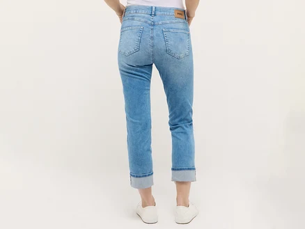 Hüfte und Beine einer Frau in hellblauen Jeans und weißen Sneakers, von hinten aufgenommen.