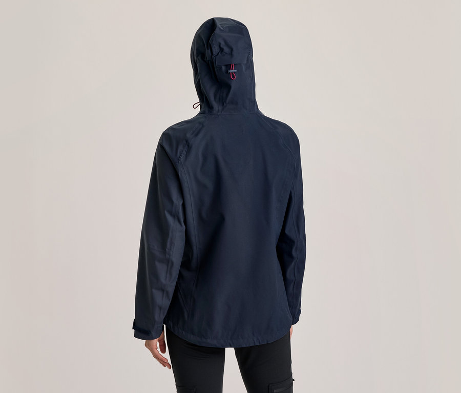 Person von hinten in einer dunkelblauen Kapuzenjacke mit rotem Detail an der Kapuze und schwarzer Hose.