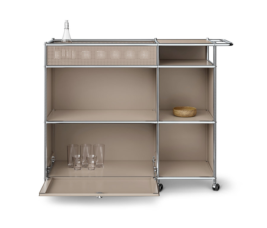 Beiger modularer Barwagen mit Chromrahmen auf Rollen, mit perforierter Oberseite, offenen Fächern und einer Klapptür, die Gläser zeigt. Eine Flasche und eine Holzschale sind ebenfalls sichtbar.