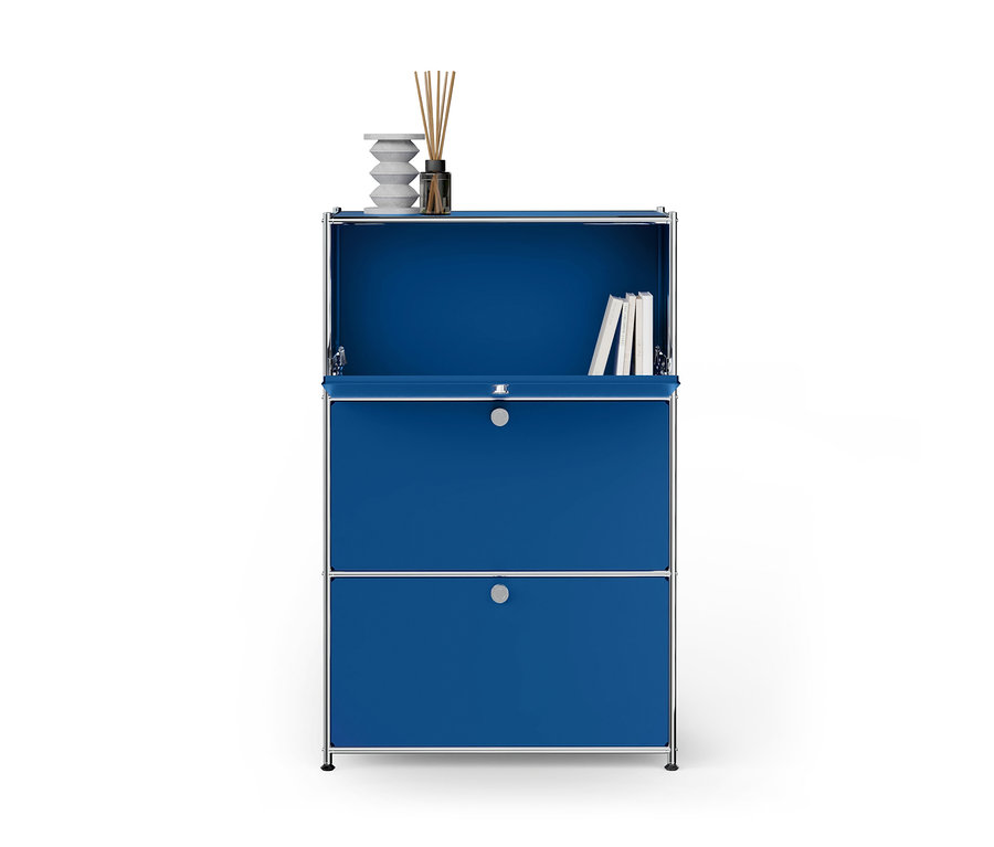 Blauer Modulschrank mit Chromrahmen. Auf der oberen Fläche stehen eine weiße Skulptur und ein Diffusor. Ein offenes Fach darunter enthält Bücher. Eine offene Klappe ist über einer geschlossenen Schublade.