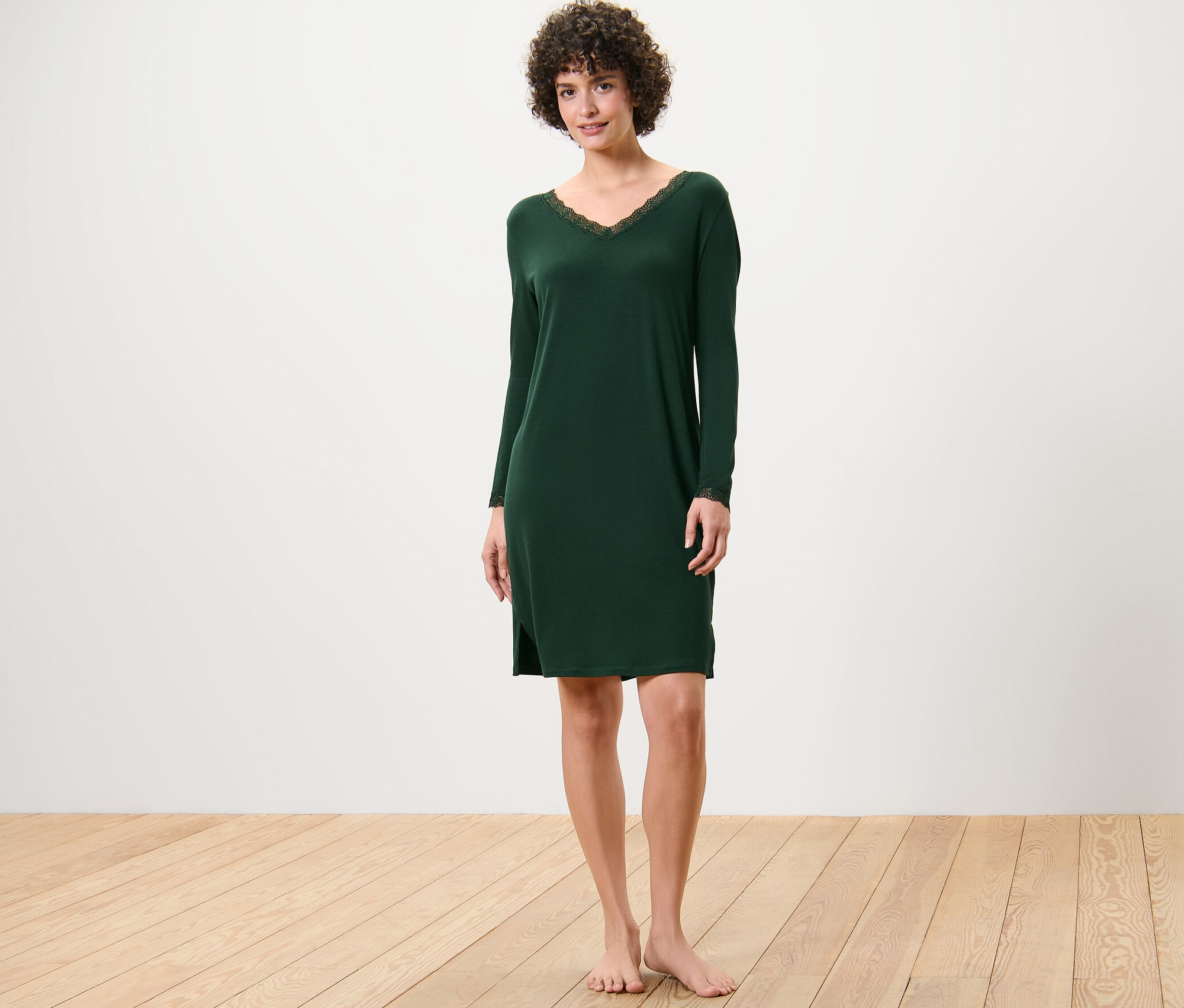Frau steht und trägt ein dunkelgrünes Nachthemd mit Spitzenbesatz.