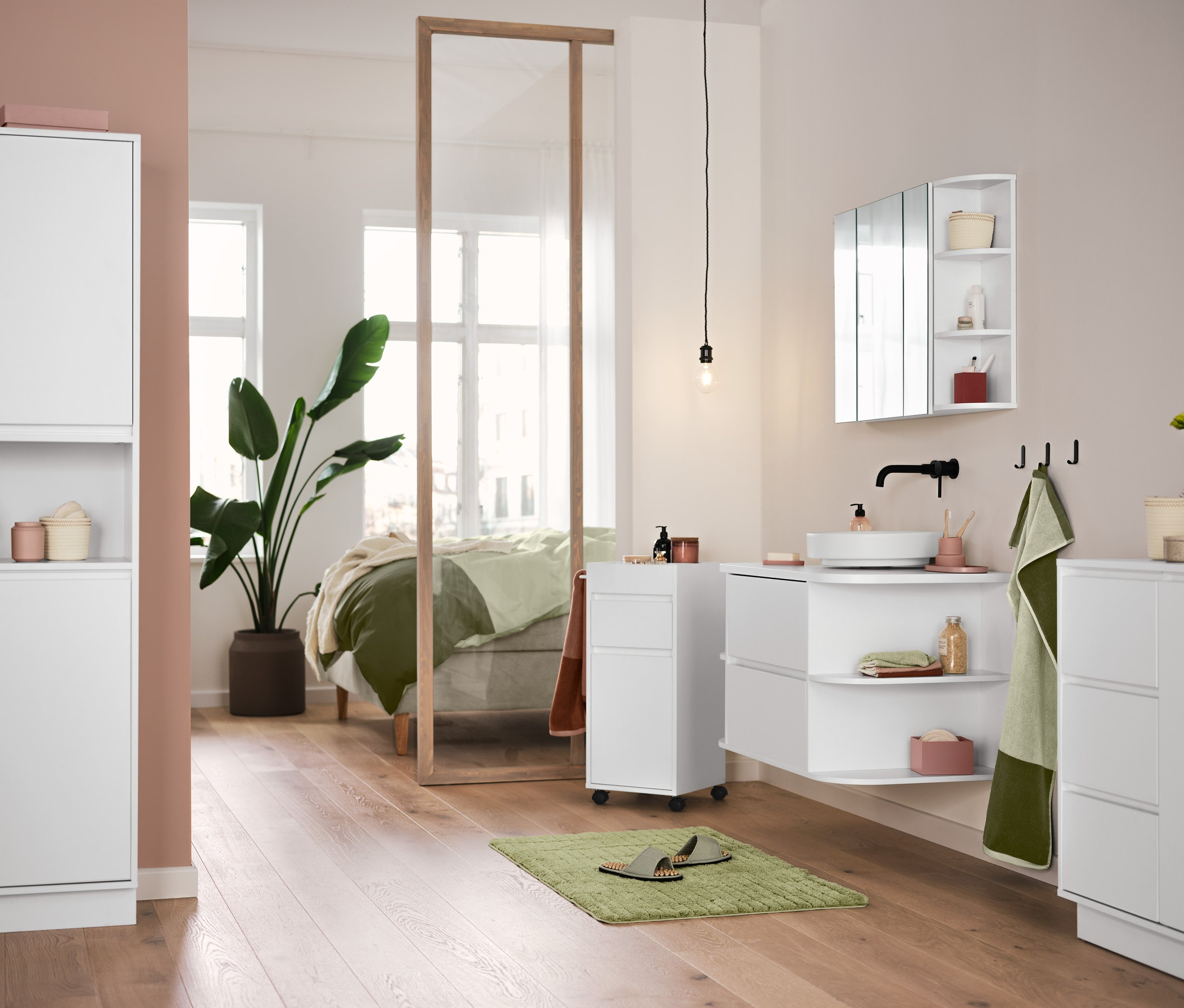 In einem Badezimmer stehen weiße Badmöbel, eine grüne Comfort-Badematte und hochwertige Jacquard-Handtücher in Sandgrün-Moosgrün hängen.