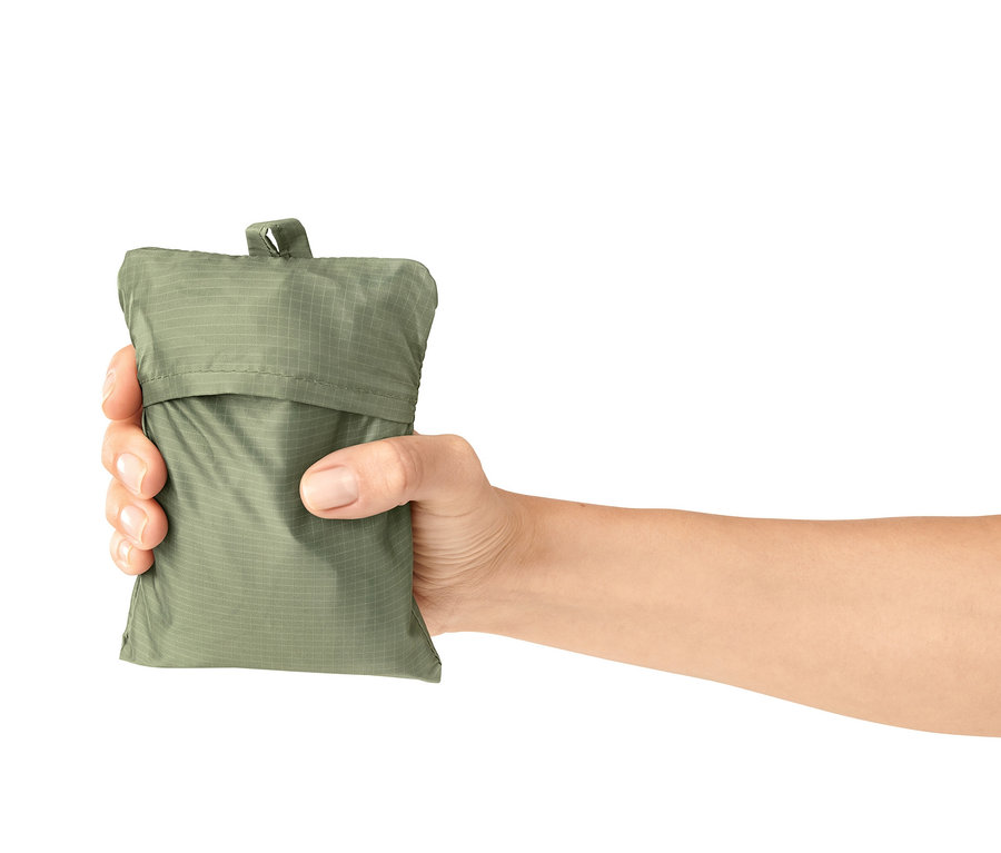 Eine Hand hält eine grüne Mini-Picknickdecke in der Verpackung.