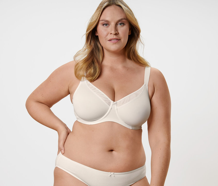 Frau posiert in einem cremefarbenen Minimizer-BH.