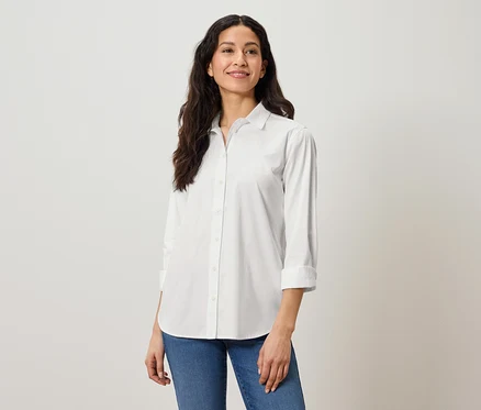 Frau mit langen dunklen Haaren trägt ein weißes Hemd und Jeans.