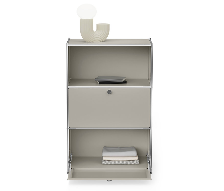Ein grauer Schrank mit silbernem Rahmen hat ein offenes unteres Regal mit gefalteter Kleidung und ein oberes Regal mit Büchern.