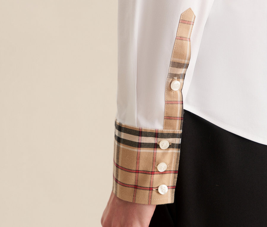 Detail einer weißen Seidensticker Popeline-Bluse mit Karodetail an Manschette und Knöpfen.