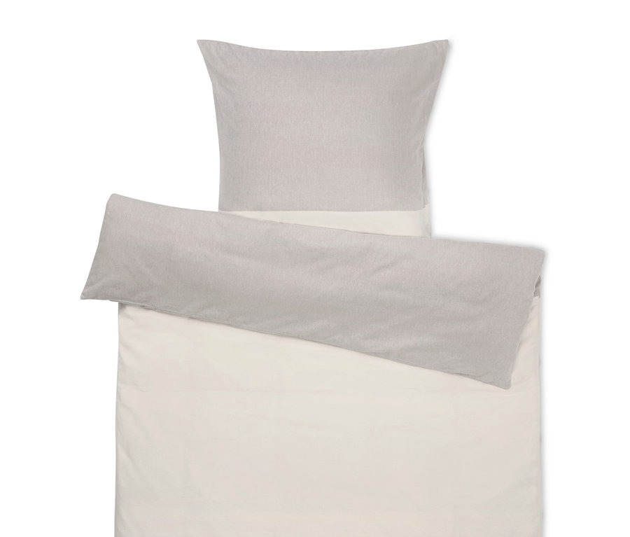 Beige Bettwäsche mit grauem Kissen oben.