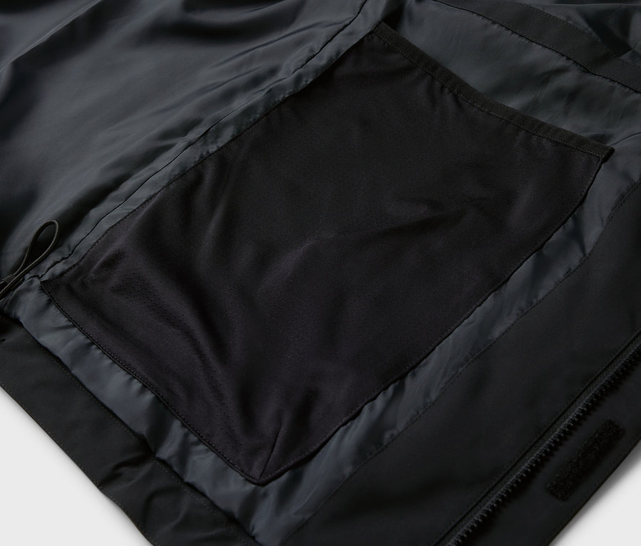 Detailaufnahme einer schwarzen Jacke mit Reißverschlusstasche.