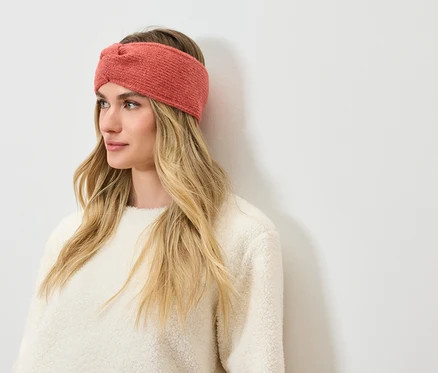 Frau mit blonden Haaren und korallfarbenem Stirnband.